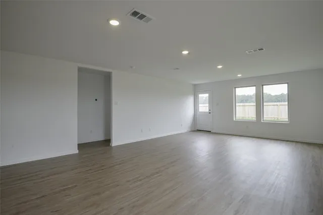 a view of an empty room with wooden floor and window