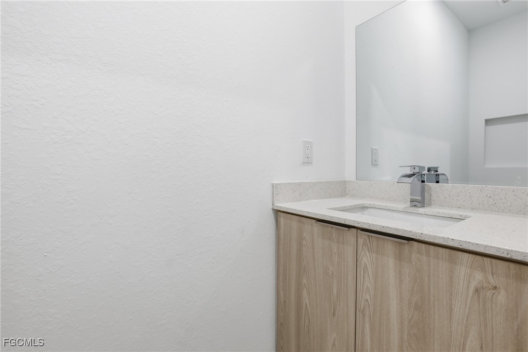 1087 Rugby Circle LaBelle, FL 33935 - Photo 17 of 19 a bathroom with a granite countertop sink and a mirror