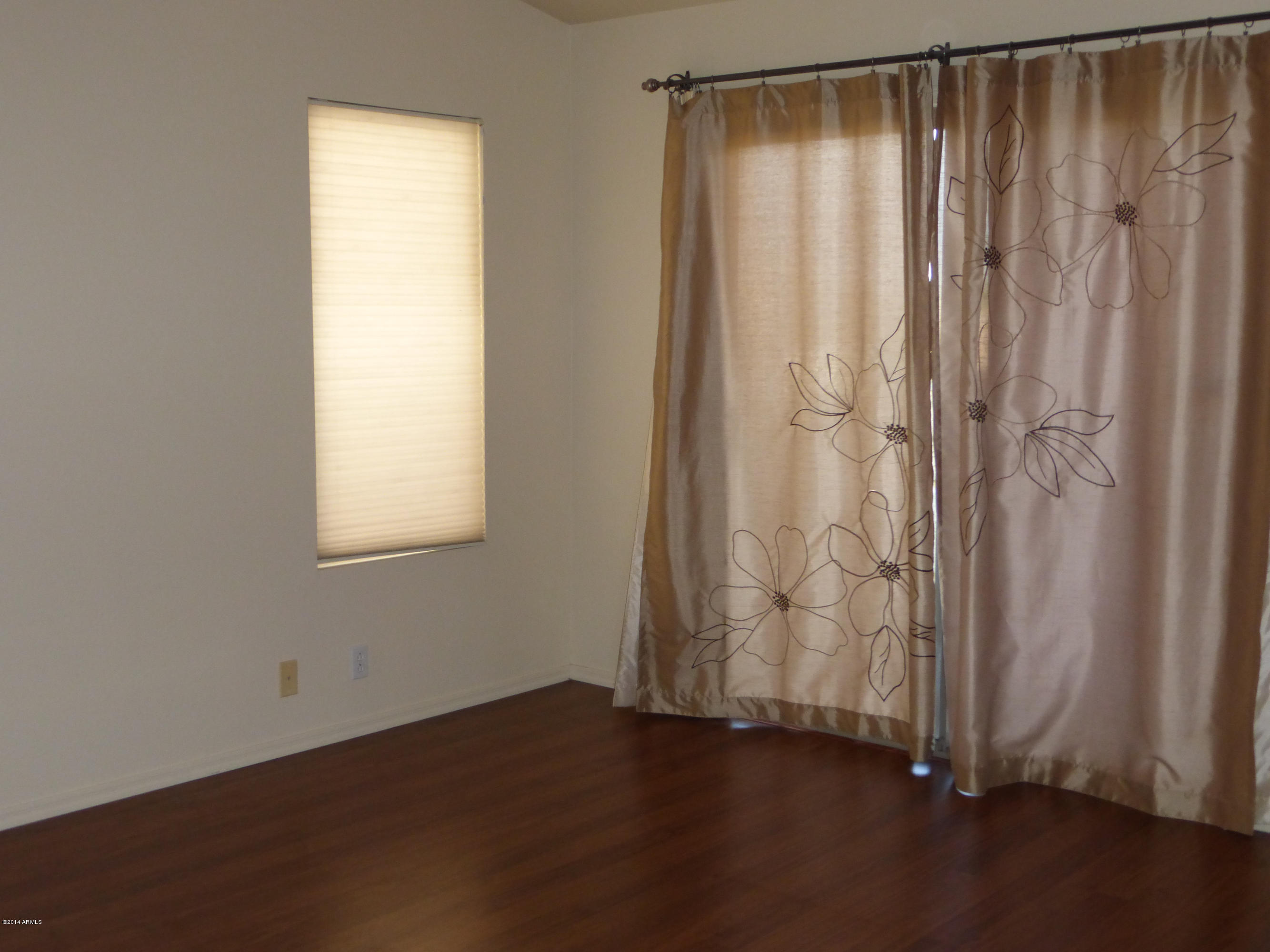 3927 East Agave Road Phoenix, AZ 85044 - Photo 9 of 21 an empty room with wooden floor and a window