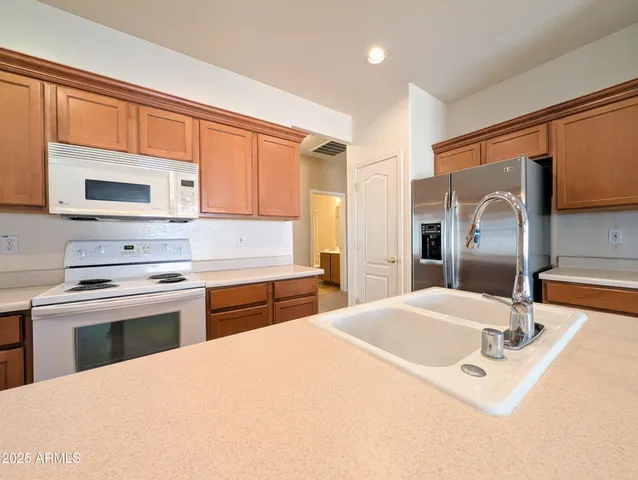 a large kitchen with kitchen island granite countertop a sink a counter top space and cabinets