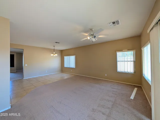 an empty room with chandelier fan and windows