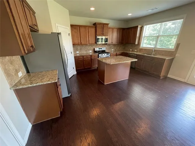 a kitchen with stainless steel appliances wooden floors and wooden cabinets