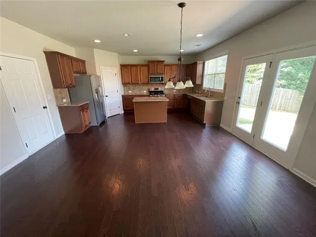 a kitchen with stainless steel appliances granite countertop wooden floors a refrigerator a sink a stove and a wooden floors