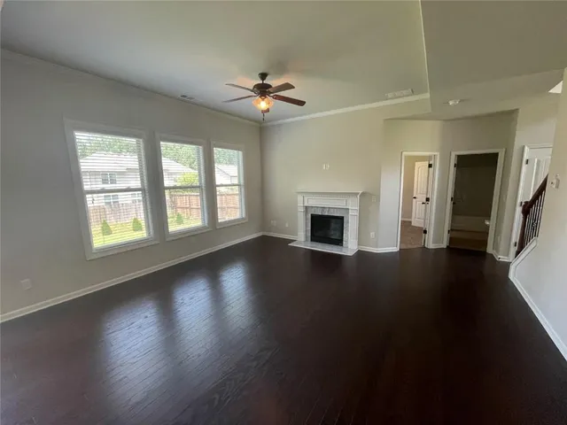 an empty room with wooden floor fireplace and windows