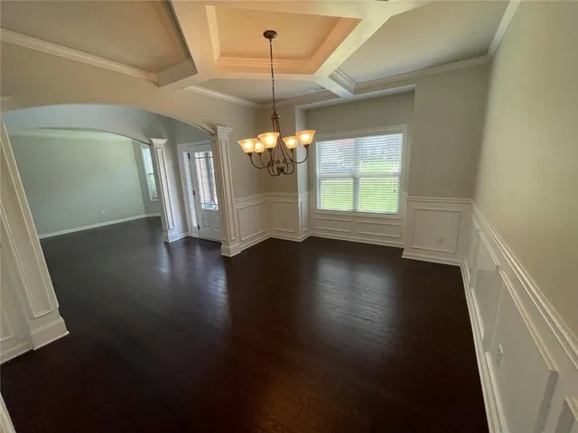 a view of a room with wooden floor chandelier and windows