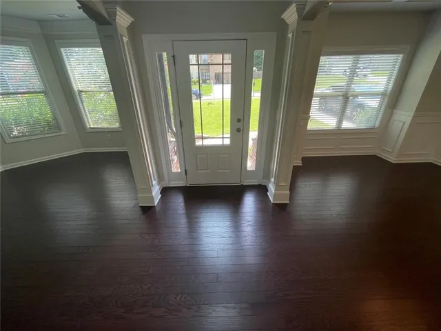 an empty room with wooden floor and windows with curtains