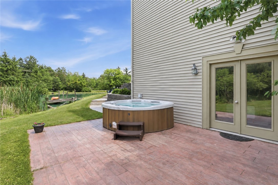 2057 Stirnie Road Victor, NY 14564 - Photo 34 of 48 Lower-level walk-out patio featuring a private hot tub, the perfect scenic spot to unwind while overlooking the property’s beautiful pond and dock!