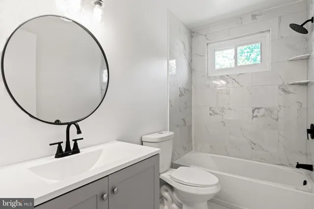 a view of an empty room with wooden floor kitchen view and a fireplace