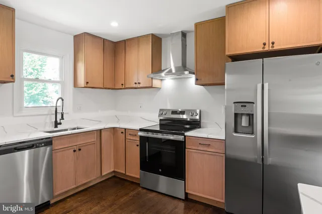 a kitchen with stainless steel appliances granite countertop a sink a stove a refrigerator and cabinets