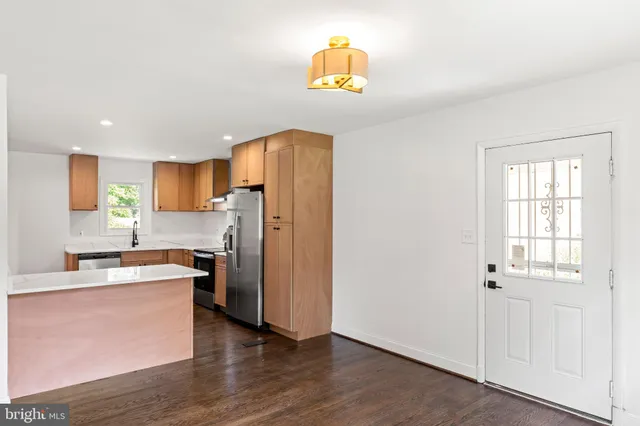 a kitchen with a refrigerator a stove a sink and wooden floor