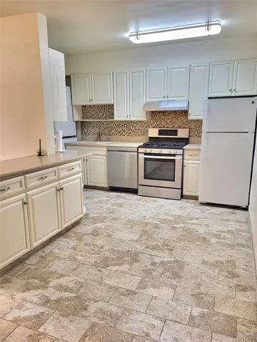 a kitchen with granite countertop a stove a sink and a refrigerator with white cabinets