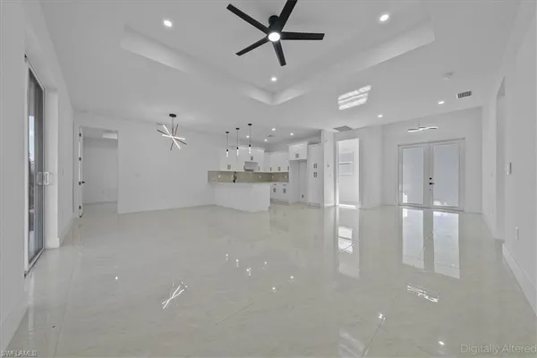 a view of an empty room with wooden floor and a ceiling fan