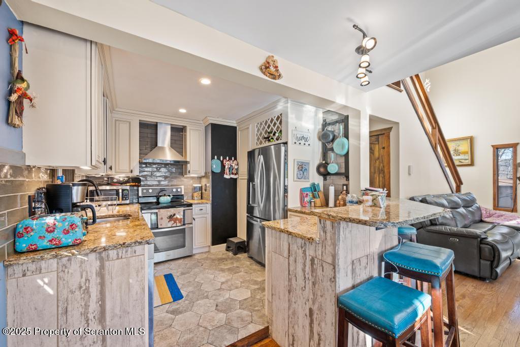 3110 Cherry Ridge Road Bushkill, PA 18324 - Photo 19 of 61 a kitchen with stainless steel appliances kitchen island granite countertop a refrigerator a stove top oven a sink dishwasher and dining table with wooden floor