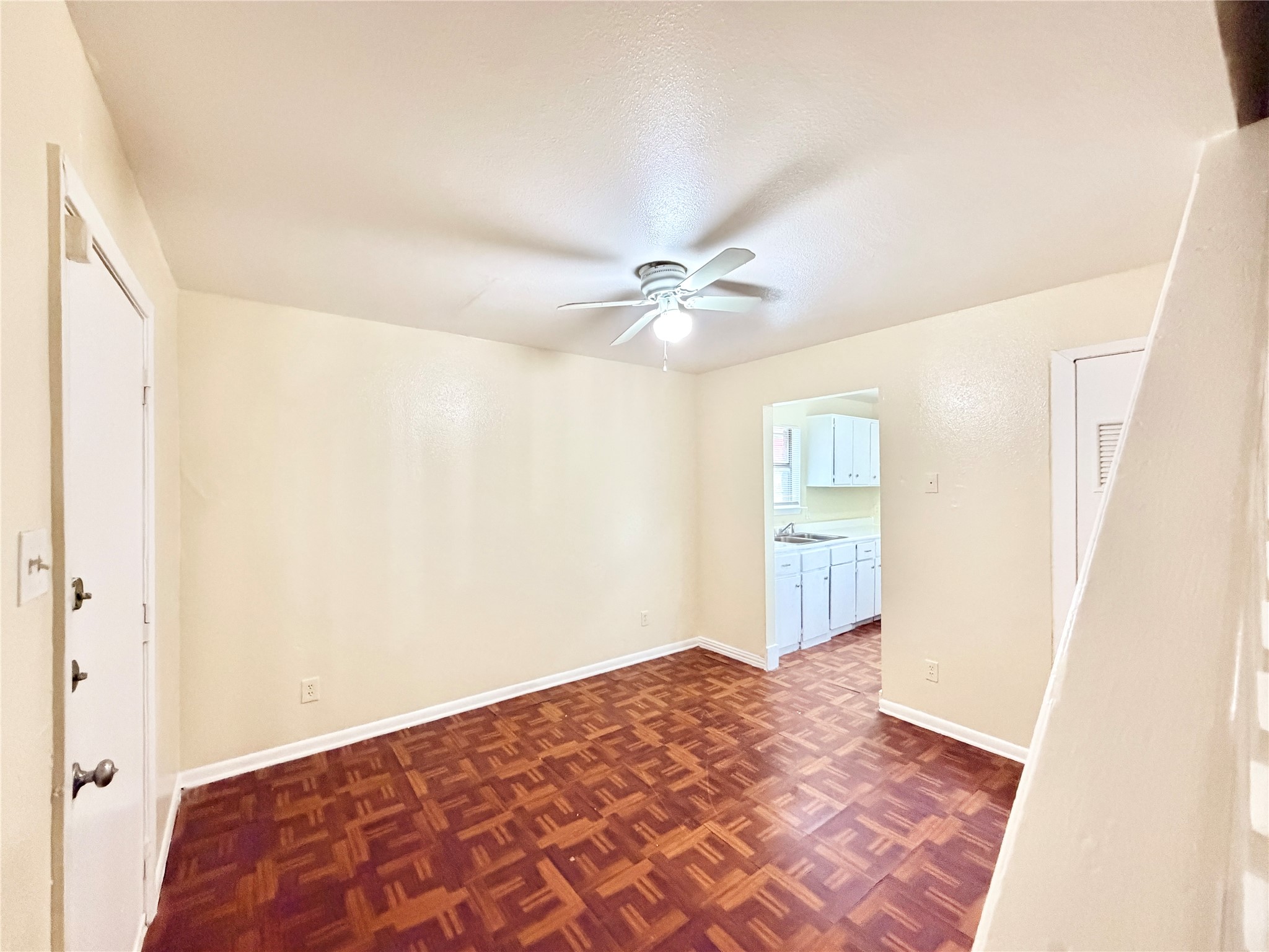 6257 Manor Road, Unit B Austin, TX 78723 - Photo 16 of 38 Living area featuring wood-finish parquet flooring, a ceiling fan, and light-toned walls
