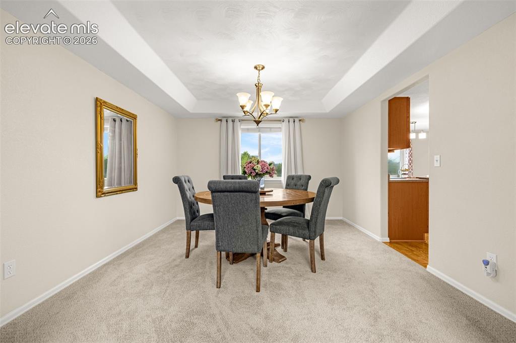 9127 Oakmont Road Peyton, CO 80831 - Photo 7 of 49 a dining room with furniture a chandelier and a window