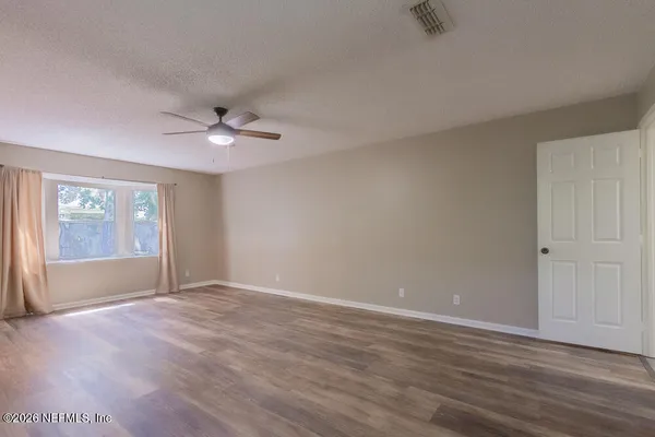 an empty room with wooden floor and windows