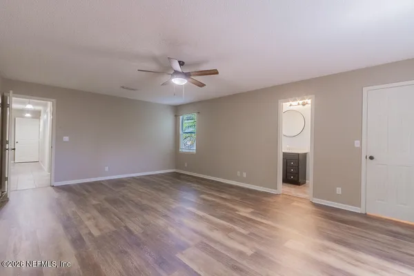 a view of an empty room with window and wooden floor