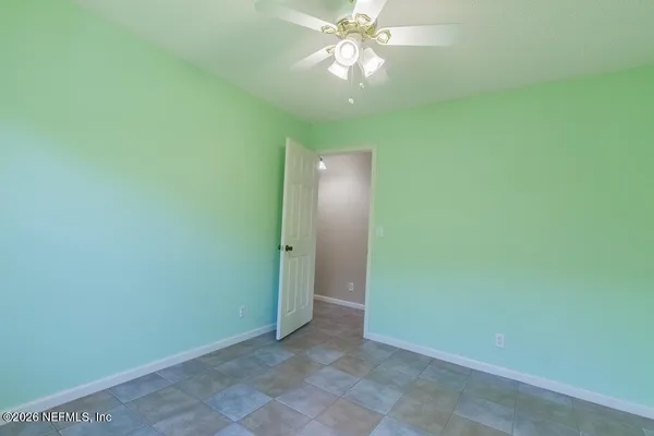 an empty room with a fan and a chandelier fan