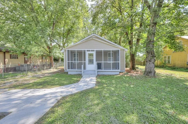 a view of a house with a yard and large trees