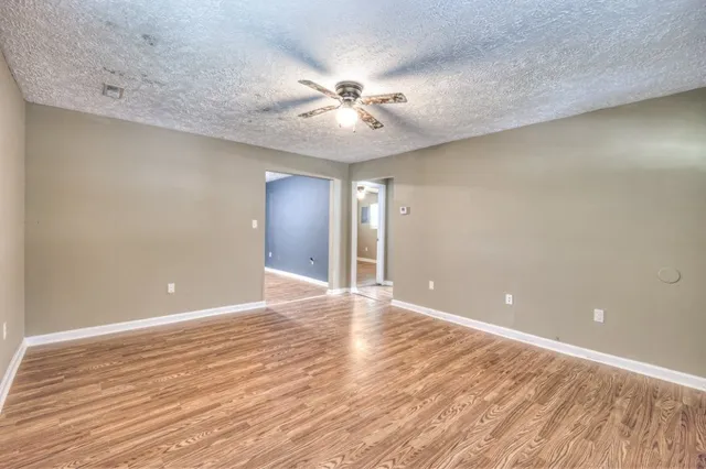 wooden floor in an empty room with a chandelier fan