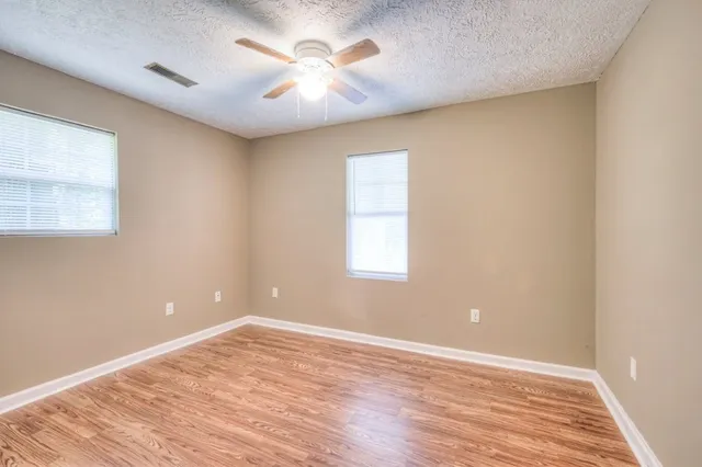 an empty room with wooden floor and windows