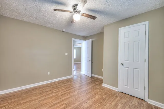 an empty room with wooden floor fan and windows