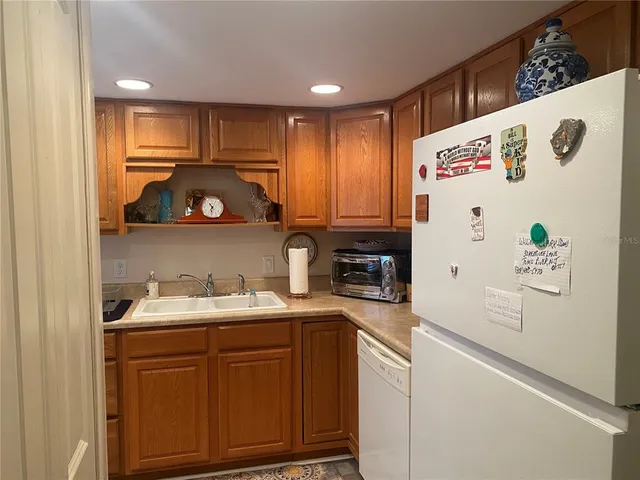 a kitchen with a refrigerator a sink and wooden cabinets