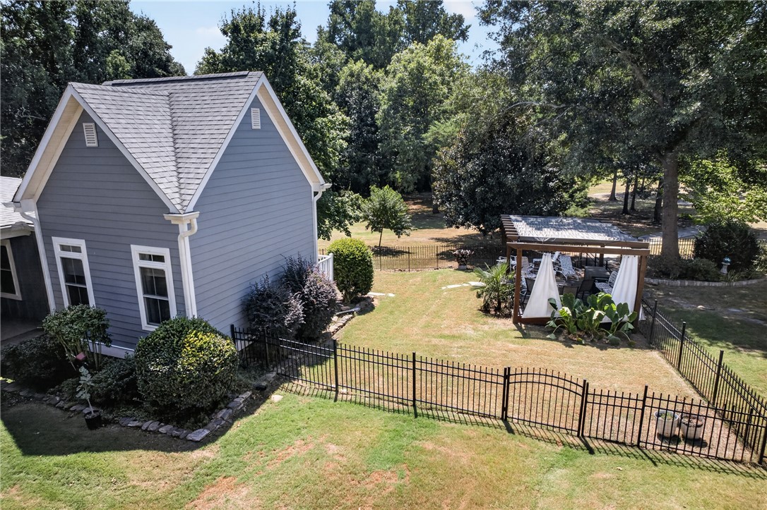 1504 Double Springs Road Townville, SC 29689 - Photo 44 of 49 Mature trees frame a grassy lawn enclosed by dark metal fencing.
