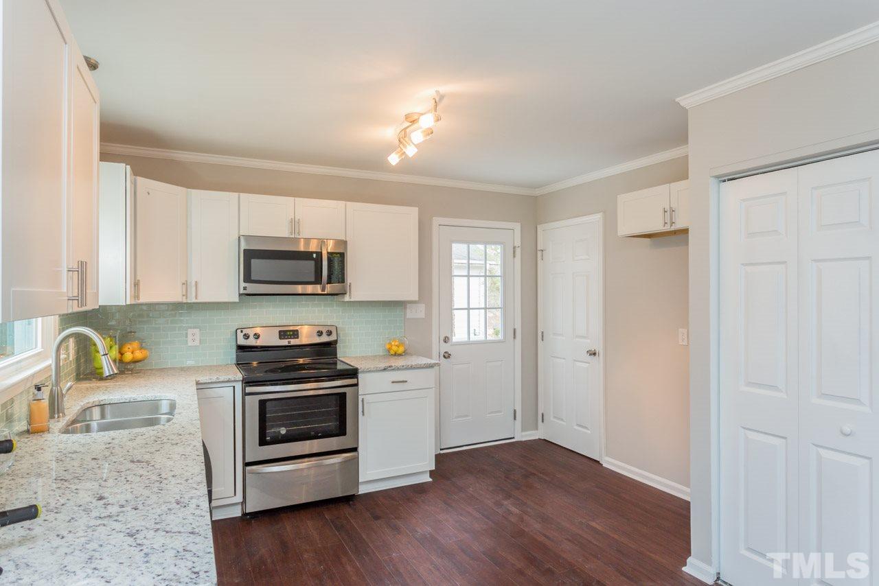 3822 Corwin Road Garner, NC 27529 - Photo 7 of 25 a kitchen with stainless steel appliances a stove a sink cabinets and a wooden floor