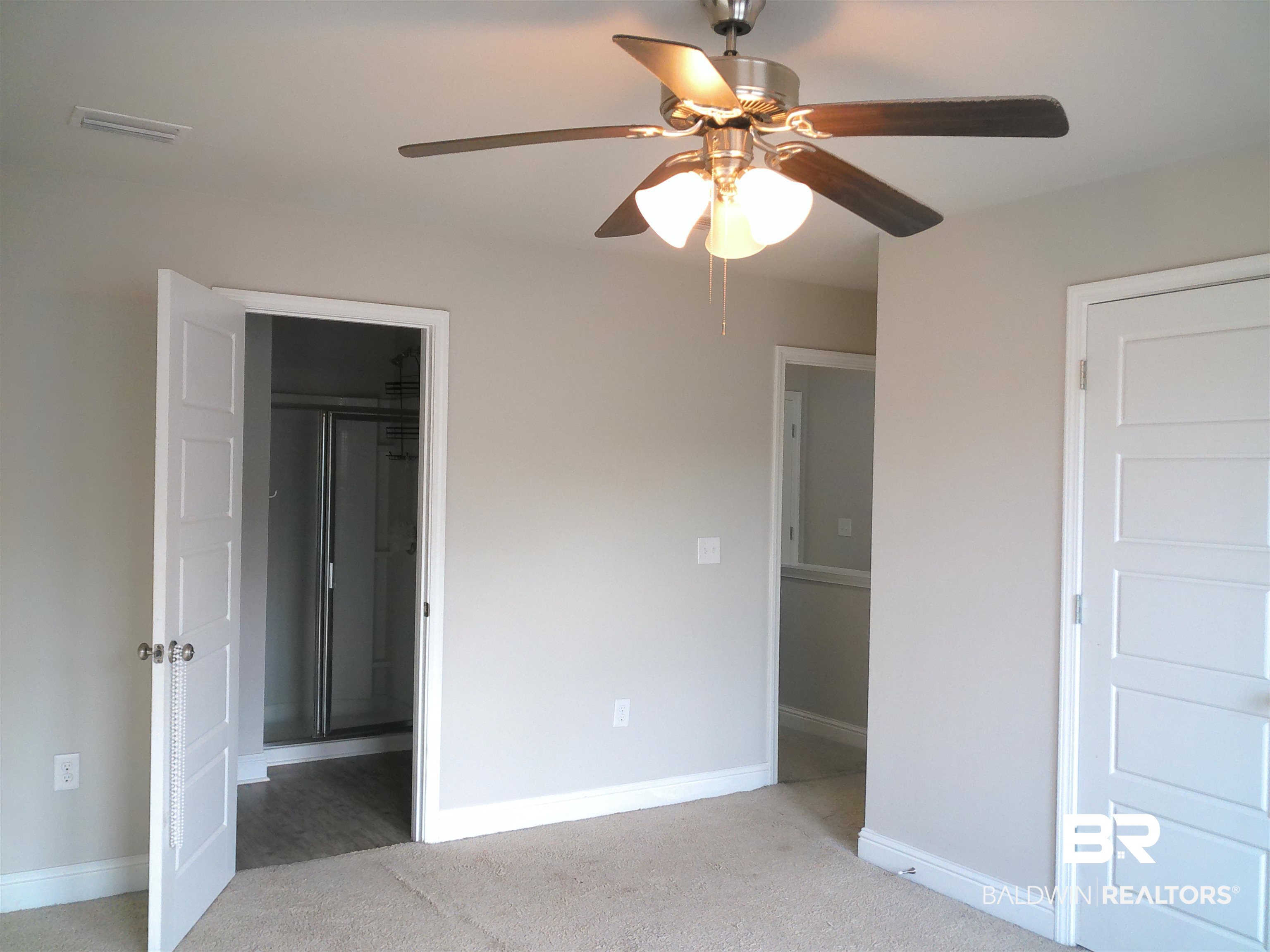25806 Pollard Road, Unit 23 Daphne, AL 36526 - Photo 4 of 16 Unfurnished bedroom featuring light carpet, connected bathroom, and a ceiling fan