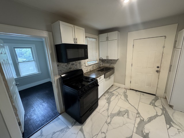 10117 South Perry Avenue Chicago, IL 60628 - Photo 21 of 33 a kitchen with granite countertop a stove a microwave a sink and cabinets