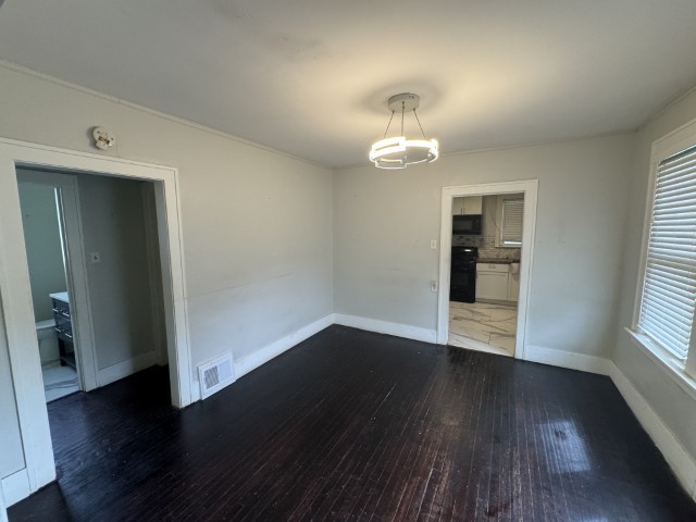 10117 South Perry Avenue Chicago, IL 60628 - Photo 10 of 33 an empty room with wooden floor and windows