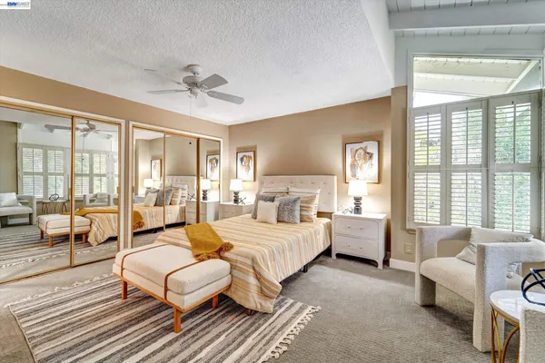 a bedroom with a bed couch and large windows