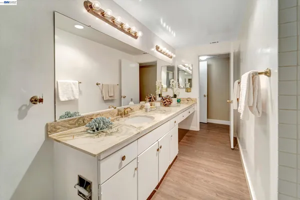 a large white bathroom with a double vanity sink a mirror and a shower