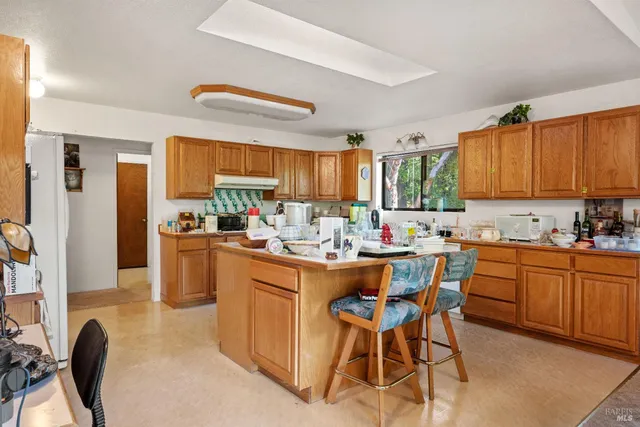 a kitchen with stainless steel appliances kitchen island granite countertop a table chairs sink and cabinets