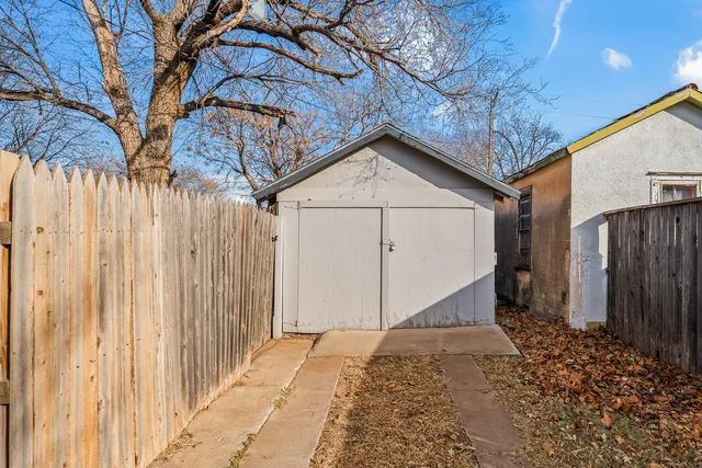 a backyard of a house with large trees and wooden fence
