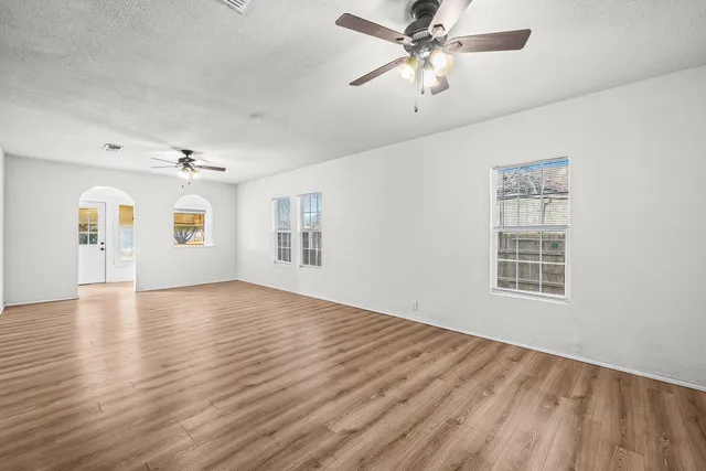 a view of an empty room with a window and wooden floor