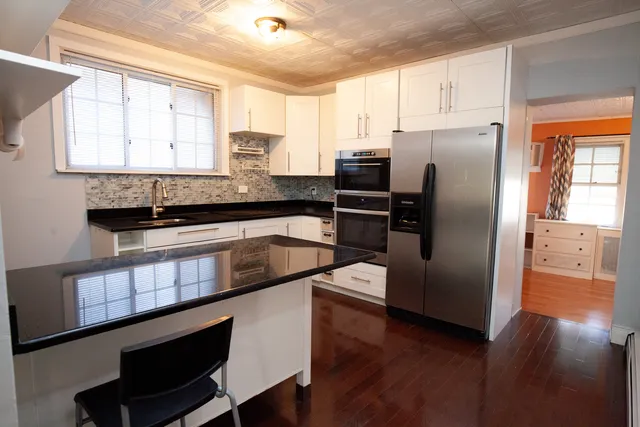 a kitchen with granite countertop a refrigerator a sink a center island and cabinets