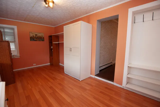 an empty room with wooden floor closet and windows