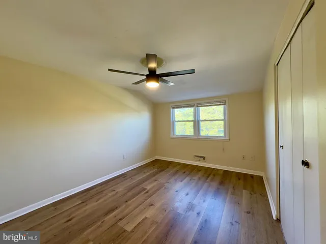 an empty room with wooden floor fan and windows