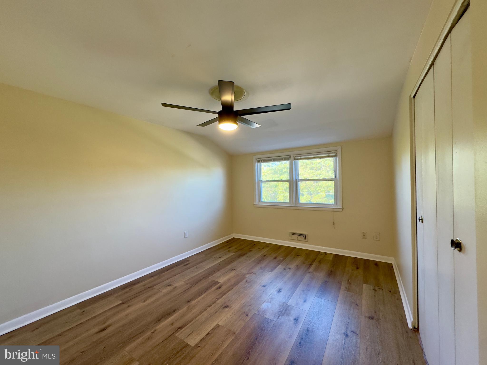 1011 Linden Avenue Baltimore, MD 21227 - Photo 17 of 20 an empty room with wooden floor fan and windows