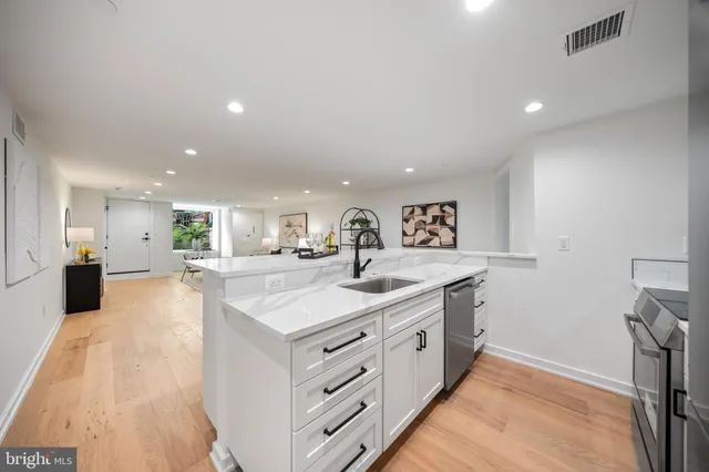 a large white kitchen with a sink and a refrigerator