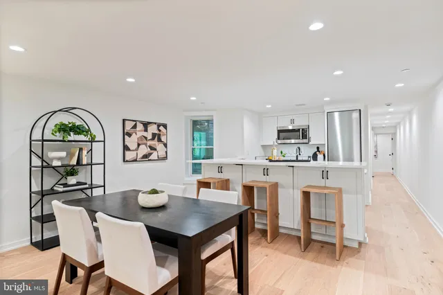 a living room with stainless steel appliances furniture a dining table and kitchen view