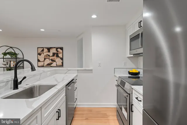 a kitchen that has a sink and a stove with wooden floor