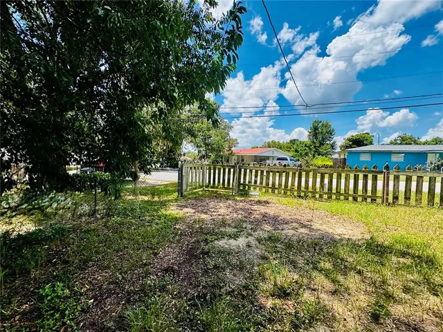 a view of a yard with flower plants and wooden fence