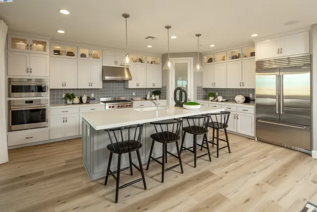 a kitchen with stainless steel appliances kitchen island granite countertop a kitchen island a stove a table and a refrigerator