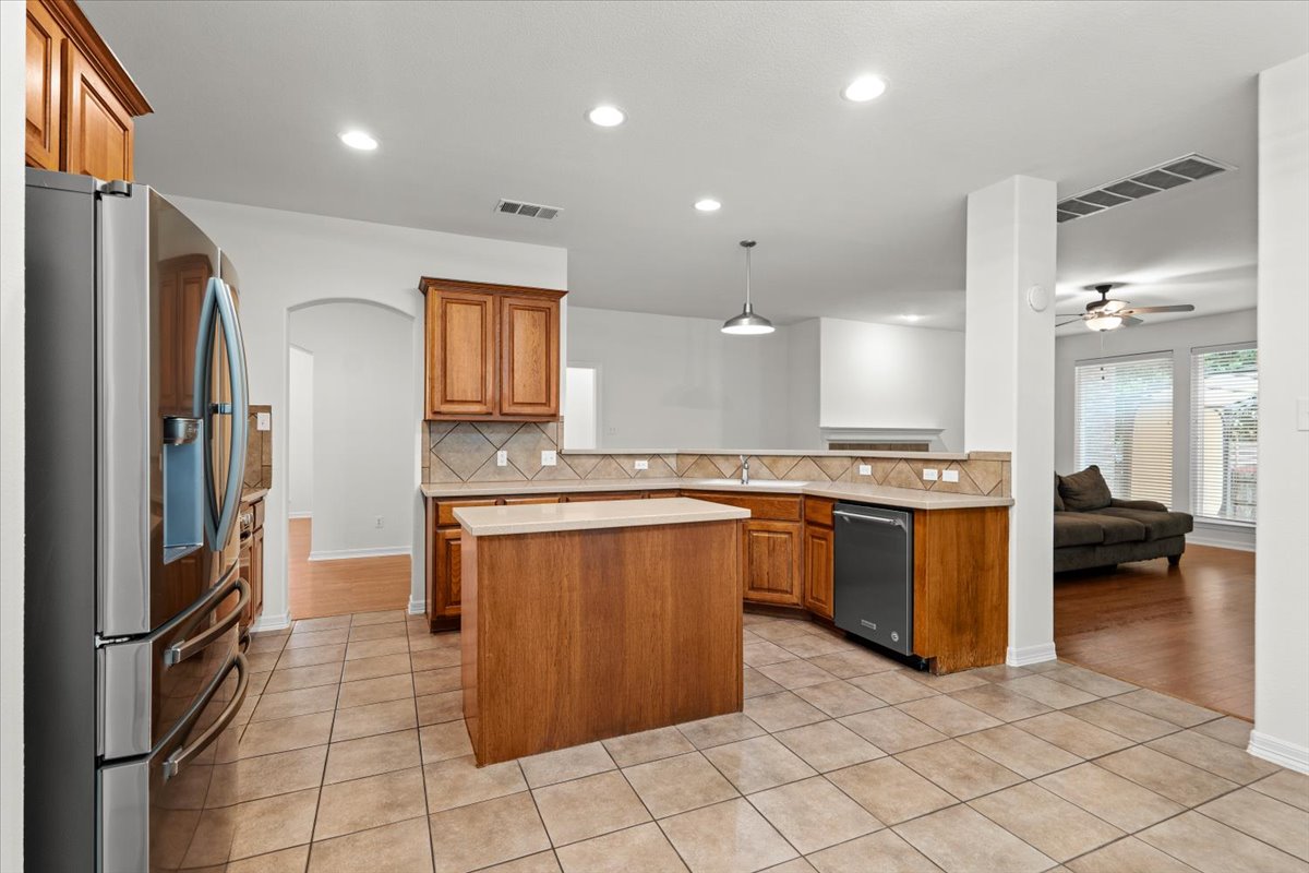 2304 Village View Loop Pflugerville, TX 78660 - Photo 13 of 40 Prepare meals in a kitchen equipped with warm wooden cabinetry and durable tile flooring, openly connecting to the living area.