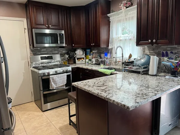 a kitchen with kitchen island granite countertop a sink stove and microwave