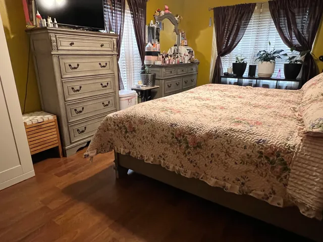 a bed sitting in a bedroom and dresser with wooden floor