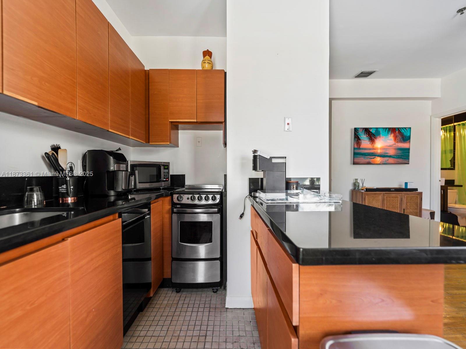1244 Pennsylvania Avenue, Unit 302 Miami Beach, FL 33139 - Photo 7 of 13 a kitchen with stainless steel appliances granite countertop a sink a stove and a refrigerator